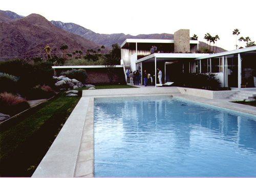 The Kaufmann Desert House in Palm Springs seen across its swimming pool, with its raised monitor roof and the San Jacinto mountains behind.