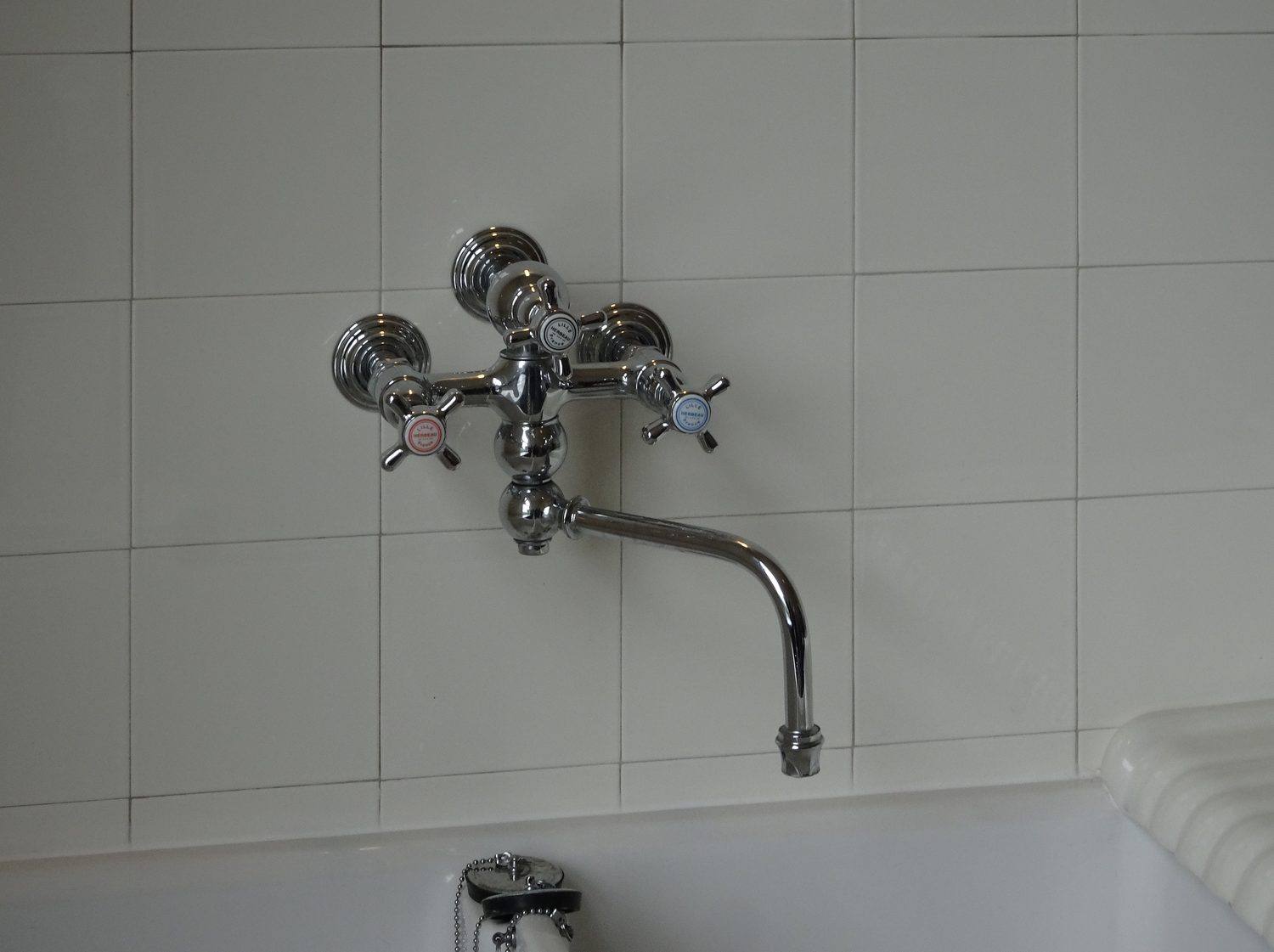 Chrome tap fittings on white tile in a bathroom at Villa Cavrois.
