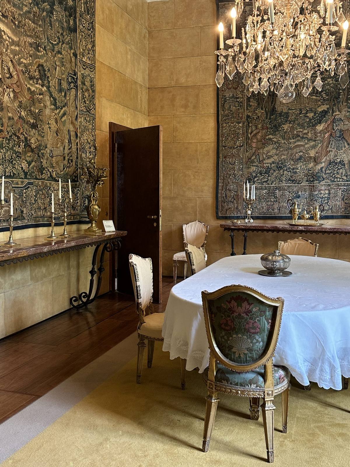 The dining room with wall tapestries, crystal chandelier and set table